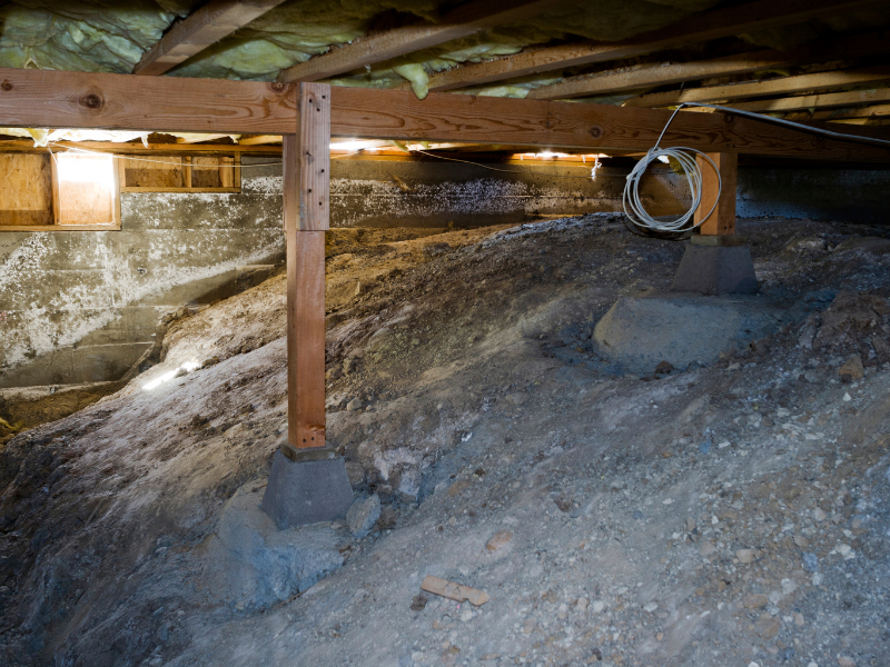 the underside of a home showing a typical dirt crawl space a common area where home inspectors and contractors might encounter asbestos debris or outdated insulation